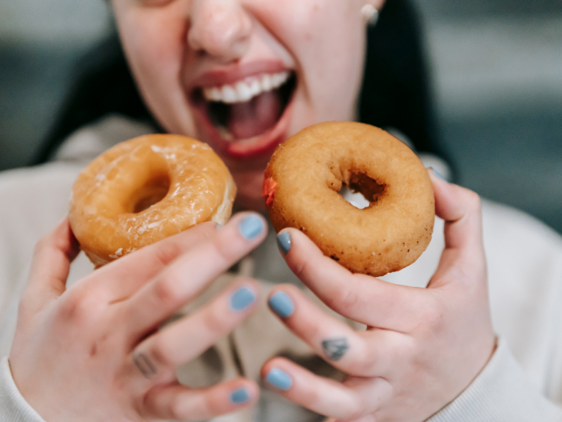 sugar and adhd: woman holding two donuts about to take a bite