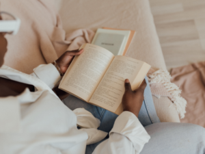 a black woman reading a book on her couch developing a reading habit