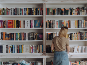 photo of woman standing in front of her home library as an example for self care ideas for bookworms