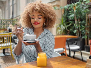 photo of woman sitting outside at a cafe with a cup of coffee self care ideas