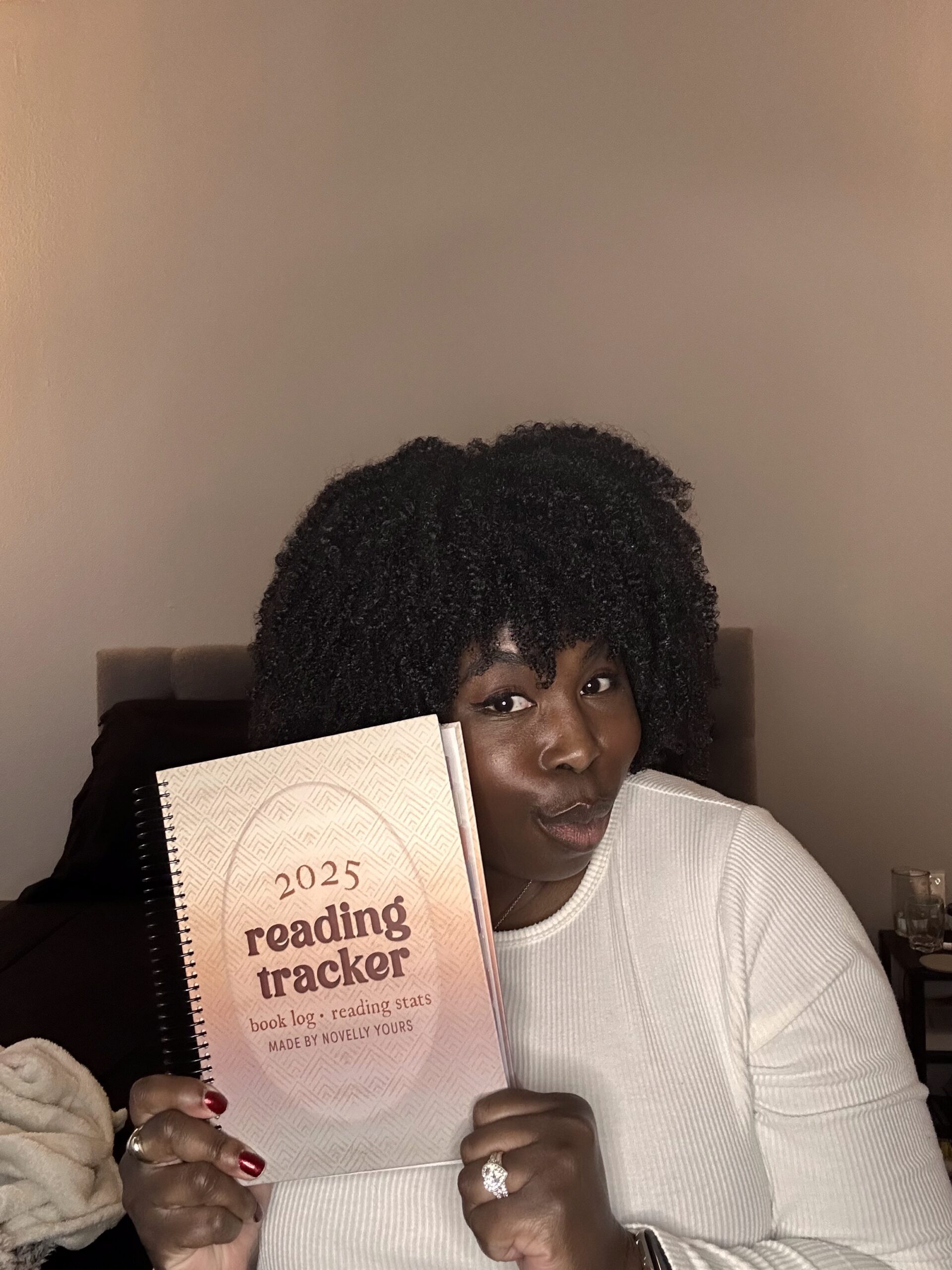 photo of kathleen haagenson wearing a white shirt holding her 2025 reading tracker