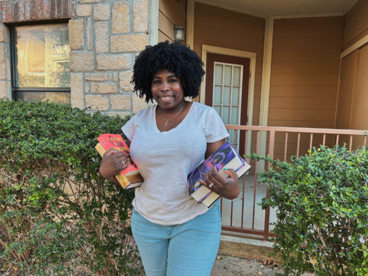 picture of Kathleen Haagenson standing outside holding books from her Spring TBR 2025