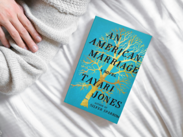 an american marriage by tayari jones laying on a white bed spread