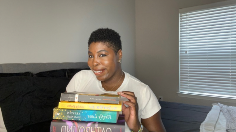 kathleen haagenson holding a stack of books she wants to read as part of her 2025 june hopefuls tbr