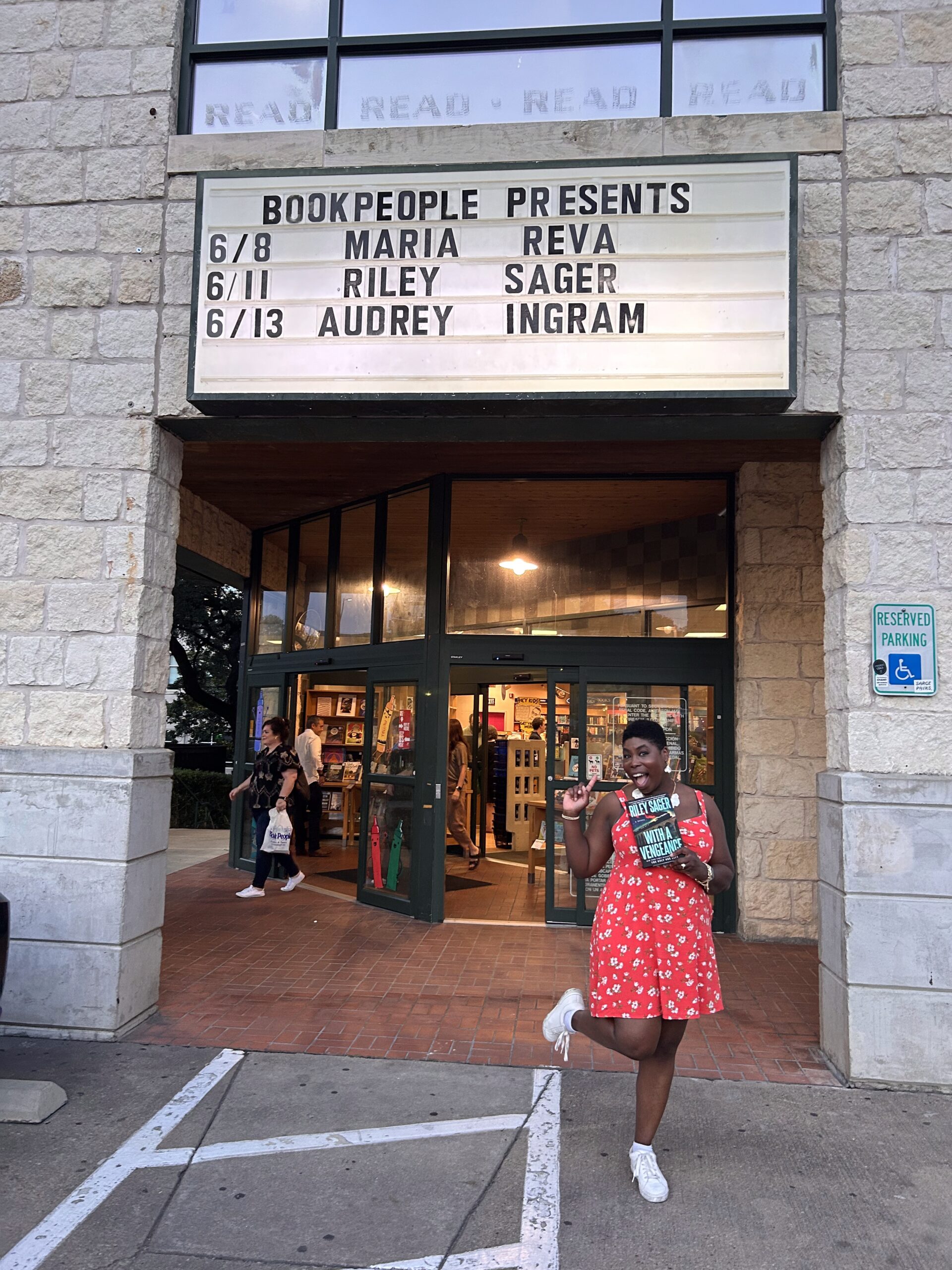 photo of kathleen haagenson in front of book people holding the new release of with a vengeance by riley sager
