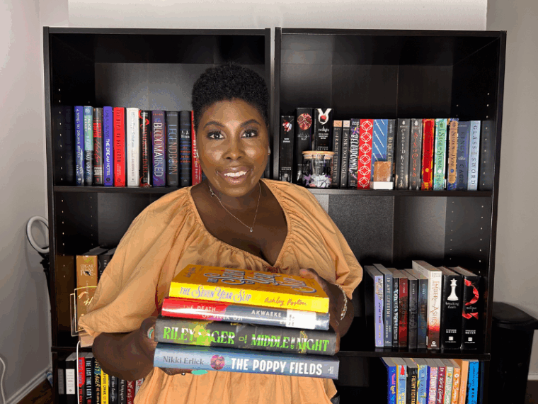 kathleen haagenson wearing an orange peasant top holding her 2025 august tbr