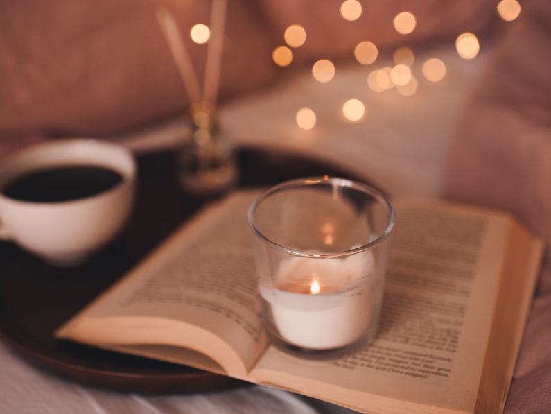 how to romanticize reading with cozy vibes featuring a candle, cup of tea and soft ambient lighting